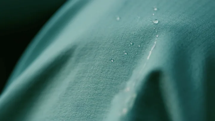 Macro of water beads on teal jacket fabric