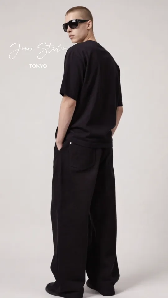 A model in a black tee, wide trousers and sunglasses