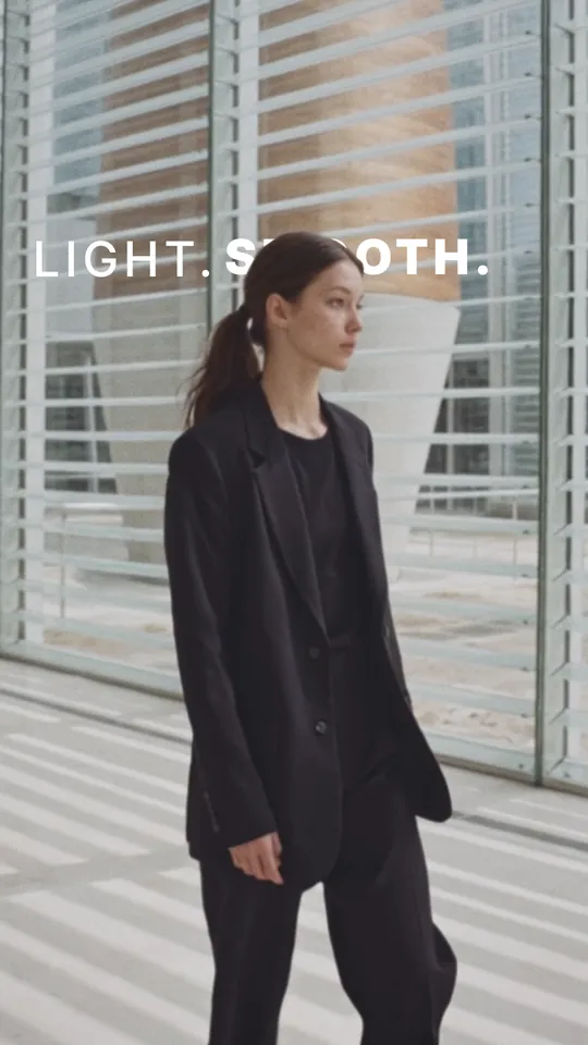 A model in a black suit by sunlit blinds — “LIGHT. SMOOTH.”