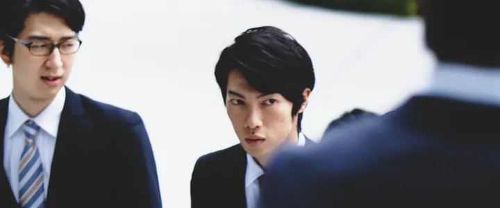 Two office workers in suits facing a colleague