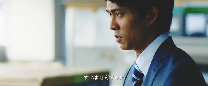 A young man in a suit apologising — 「すいませんでした」