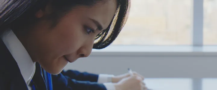 A woman leaning over a desk, writing intently