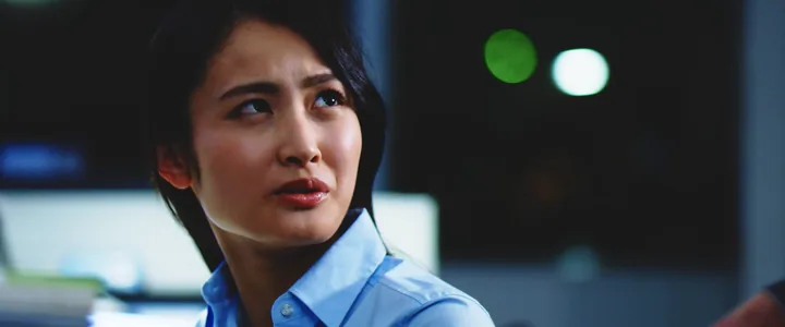 A woman in a blue shirt looking up, worried