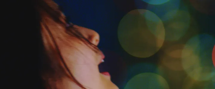 A woman laughing among warm bokeh lights