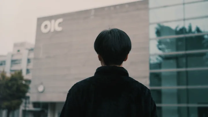 A student seen from behind in front of a campus building