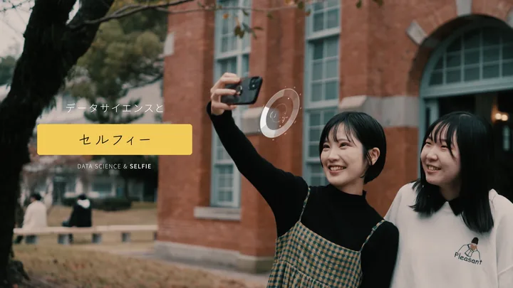 Two students taking a selfie in front of a red-brick building