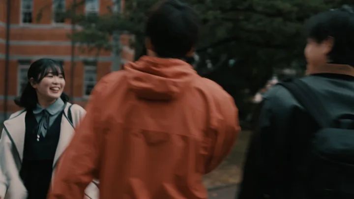 Students in orange and black jackets laughing on campus