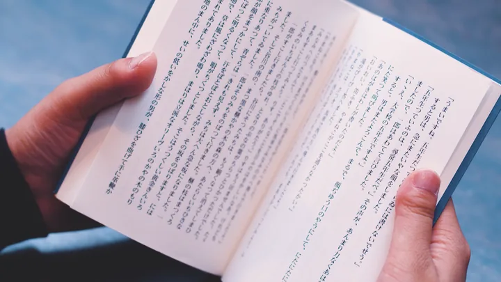 Hands holding an open Japanese paperback