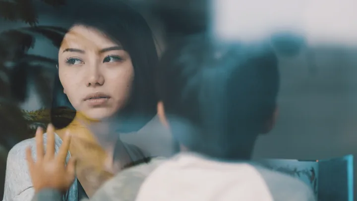 A woman's face reflected in a window, a child beside her
