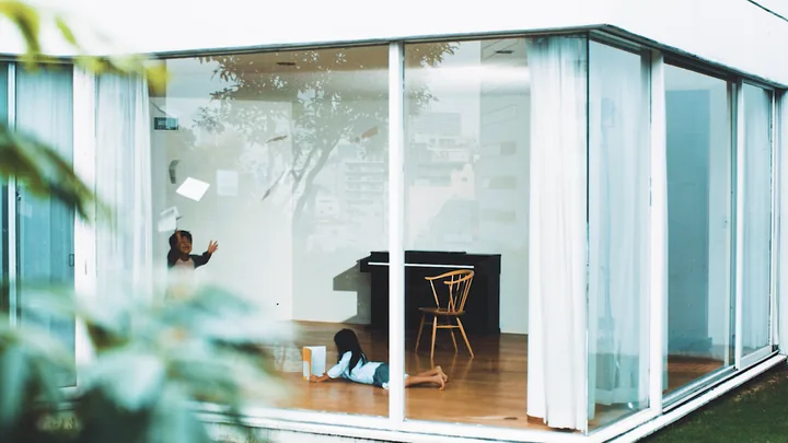 A girl reading on the floor of a glass-walled room