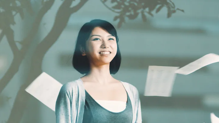 A woman smiling among floating sheets of paper