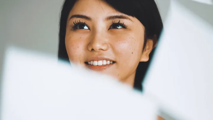 A woman smiling up through flying white paper