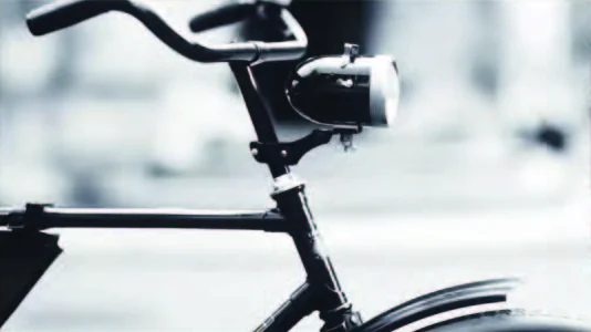 A vintage bicycle's lamp and handlebars in black and white