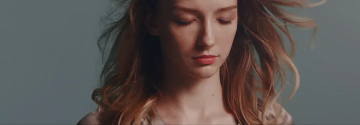 A young woman with windswept hair looking down