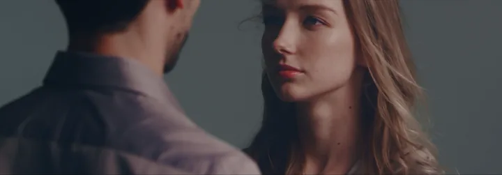 A couple standing close, her gaze on him
