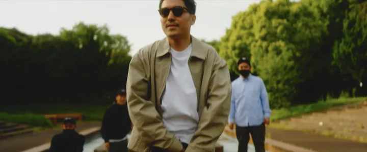 A man in a beige jacket stepping forward in a park