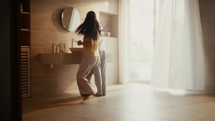 A woman by the bathroom mirror in soft morning light
