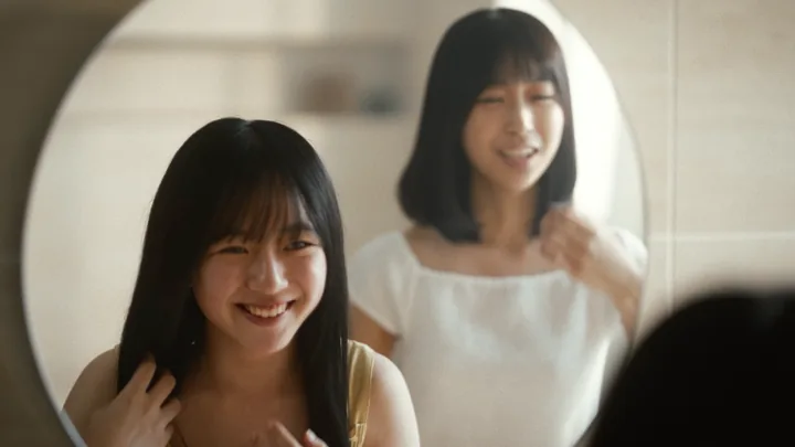 Two girls smiling in front of a round mirror