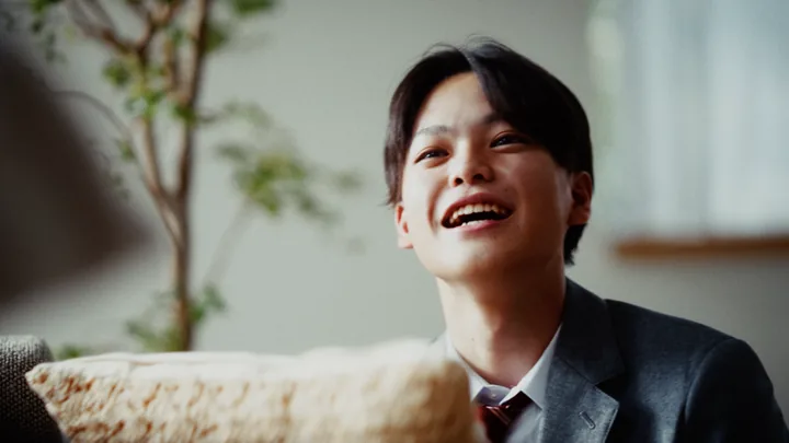A young man in a school blazer laughing