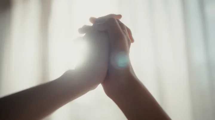 Two hands clasped against the light