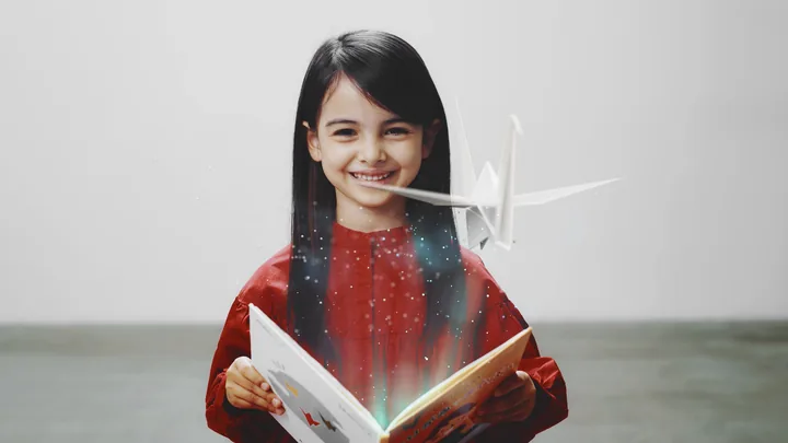 The girl smiling as paper cranes rise from the book