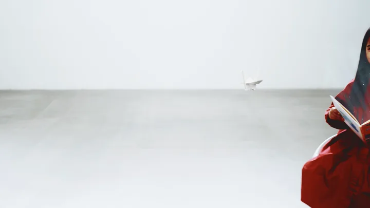 A paper crane flying across an empty white room