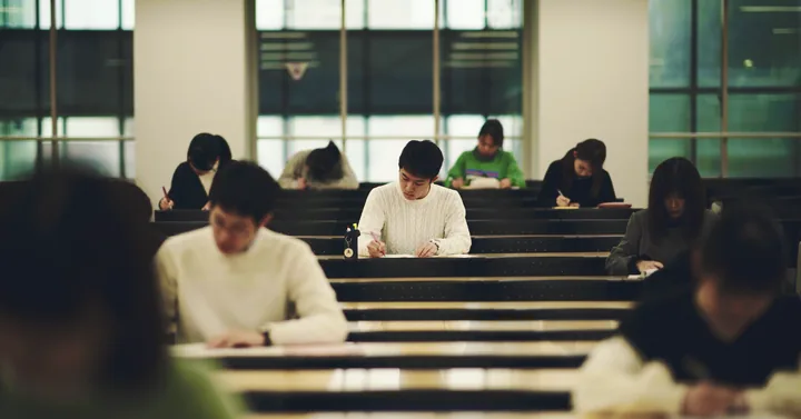 Students writing in a tiered lecture hall