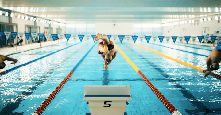 A swimmer diving off the blocks in an indoor pool