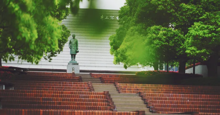 The statue above the amphitheatre steps, framed by green leaves
